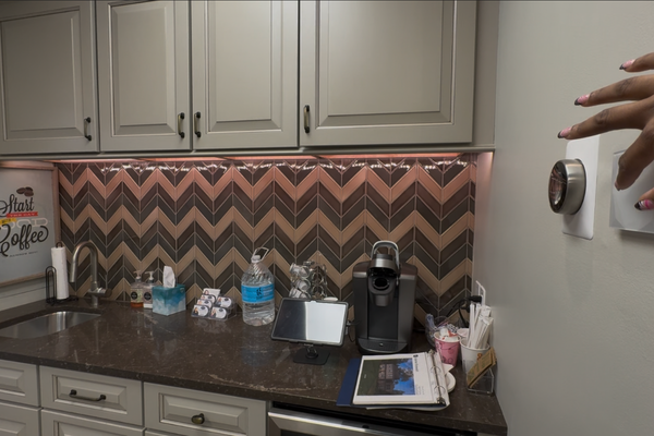 Image of remodeler's showroom kitchen with a hand controlling the lighting with wall controls